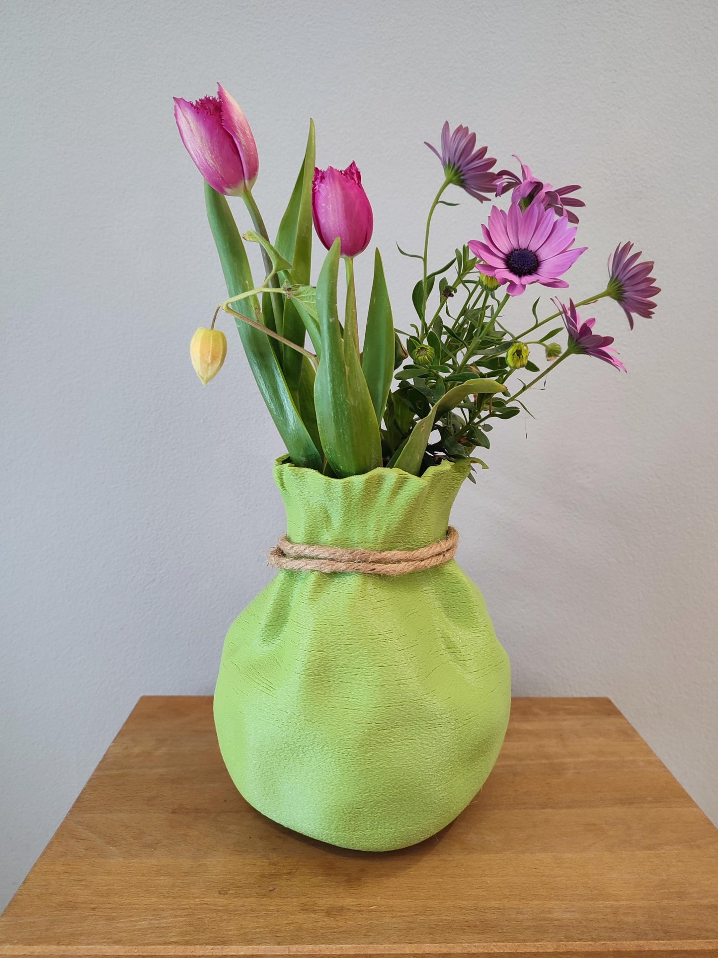 Modern, whimsical, pastel green vase in the shape of a bag.